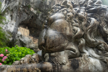 Entrance to the Covadonga cave and hermitage, framed by lush greenery and a lion statue in Asturias, Spain