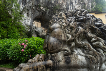 Entrance to the Covadonga cave and hermitage, framed by lush greenery and a lion statue in Asturias, Spain