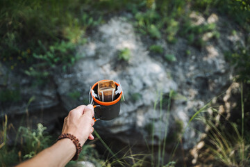 In the peaceful outdoors, find tranquility holding an enamel cup and leather wallet, surrounded by wild beauty. Enjoy nature while exploring the serene wilderness