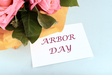 Arbor Day message. text on a white business card on a blue background in a composition with a bouquet of flowers