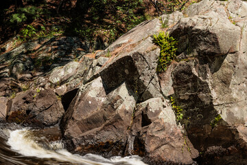 A large boulder creates one shoreline for the rushig water of the Pike River to flow over and past on Three Foot Falls within Twelve Foot Falls County Park near Dunbar, Wisconsin