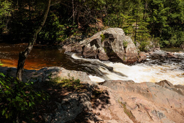 Looking at Three Foot Falls within Twelve Foot Falls County Park near Dunbar, Wisconsin in early June, as the Pike River flows fast from the spring runoff, through the boulder-lined shoreline