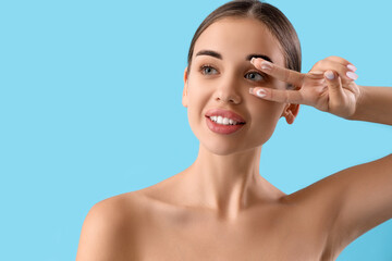 Young woman with natural cream on her fingers against light blue background