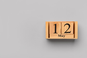 Wooden cube calendar with date 12 MAY on grey background. Top view