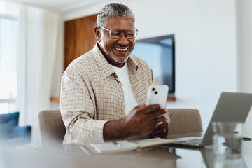 Happy mature male using phone for connecting and staying in touch