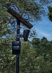 License plate recognition camera: Device blends in with surroundings. The camera, mounted on a black pole, records license plate data of vehicles passing by.