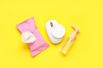 Bottle of sanitizer with mouse and wet tissues pack on yellow background