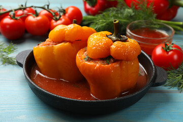 Tasty stuffed peppers and products on light blue wooden table, closeup