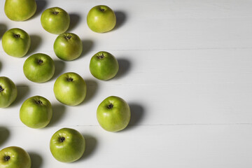 Fresh ripe green apples on white wooden table. Space for text