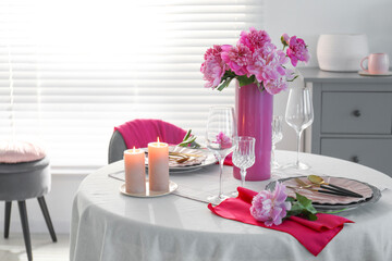 Beautiful table setting with pink peonies and burning candles