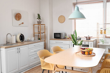 Interior of stylish kitchen with dining table, chairs and lamp