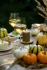 Fall still-life. Orange pumpkins, dry flowers and candles on linen tablecloth. Dinner table outdoors in the garden. Cozy autumn concept., simple handmade decoration, countryside style