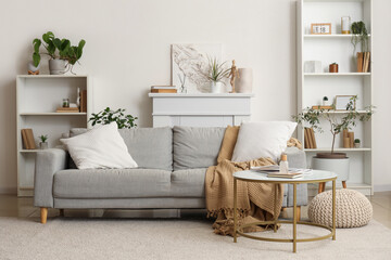 Interior of cozy living room with grey sofa and reed diffuser on coffee table