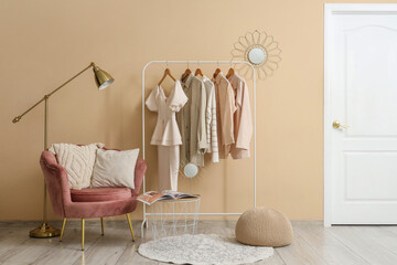 Stylish living room with pink armchair, coffee table, lamp and rack of clothes