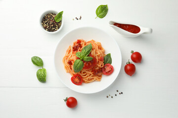 Delicious pasta with tomato sauce, peppercorns, vegetables and basil on white wooden table, flat lay