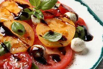 Tasty salad with balsamic vinegar and mozzarella on plate, closeup