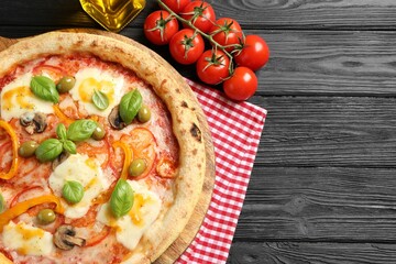 Delicious vegetarian pizza served on black wooden table, top view. Space for text