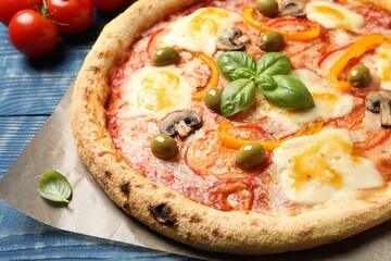 Delicious vegetarian pizza and ingredients on blue wooden table, closeup