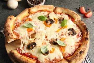 Taking piece of delicious vegetarian pizza at grey table, closeup