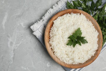 Tasty cooked rice in bowl with parsley on grey marble table, flat lay. Space for text