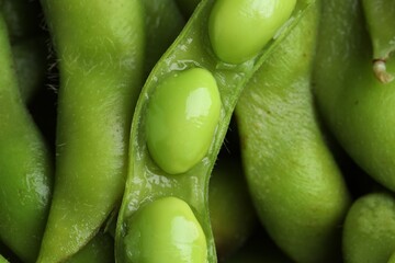 Fresh edamame pods with soybeans as background, top view