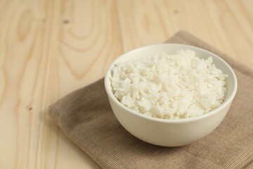 Delicious boiled rice in bowl on wooden table