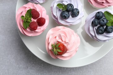 Tasty cupcakes with different berries on light grey table, top view