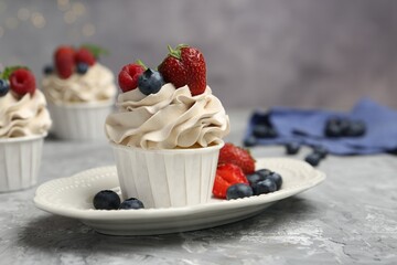 Tasty cupcakes with different berries on light grey table, closeup