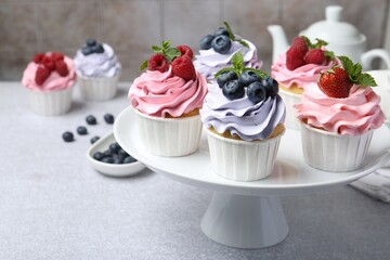 Tasty cupcakes with different berries on light grey table, closeup. Space for text