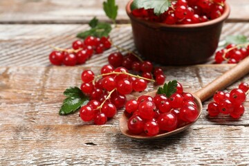 Fresh red currants and green leaves on wooden table, closeup