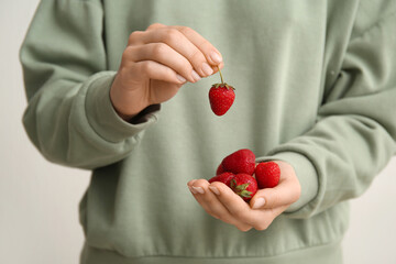 Woman with sweet fresh strawberries on grey background, closeup