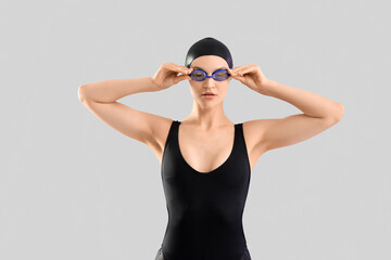 Professional young female swimmer on grey background