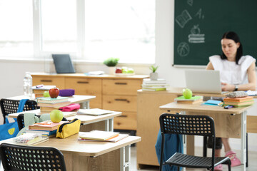 Apple with books and pencil case on desk in classroom, closeup