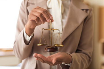 Female lawyer with justice scales in office, closeup