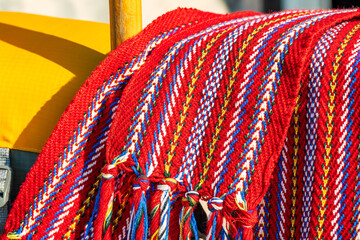 ceinture fléchée (traditional pattern) replica of the woven sash worn by voyageurs during the fur trade shot on a rail with orange pfd's and wooden canoe paddles room for text