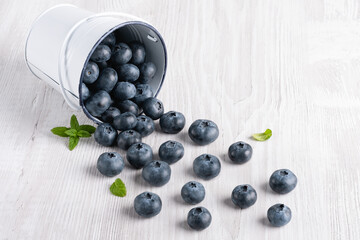 Blueberries poured from a small bucket on a white background