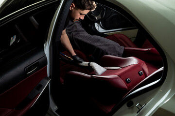Detailing auto seats with special hoover nozzle. Hoovering car backseat with vacuum extractor.