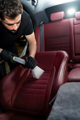 Detailing auto seats with special hoover nozzle. Hoovering car backseat with vacuum extractor.