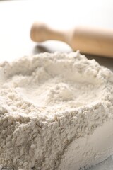 Pile of flour and rolling pin on grey marble table, closeup