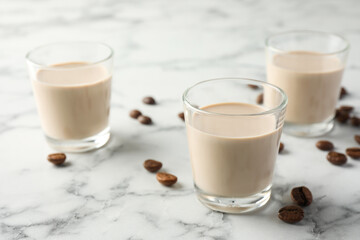 Coffee cream liqueur in glasses and beans on white marble table