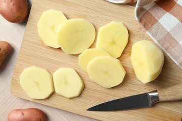 Fresh raw potatoes and knife on wooden table, top view