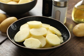 Whole and cut fresh raw potatoes on wooden table