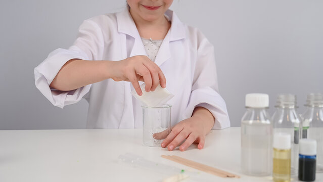 Faceless girl doing chemical experiments on a white background.