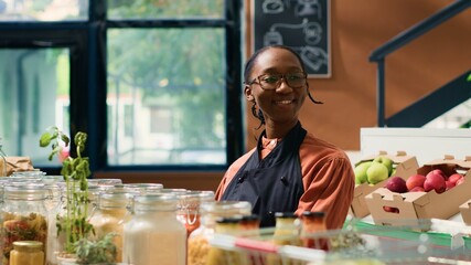 Happy local grocery store woman vendor arranging freshly harvested organic products on shelves....