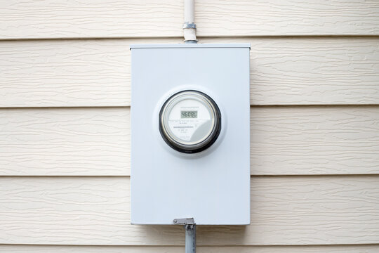 Power meter box mounted on a wall. Kilowatt-hour electric meter installed outside of a house.