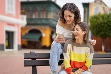 Two friends laughing while watching something funny on mobile phone