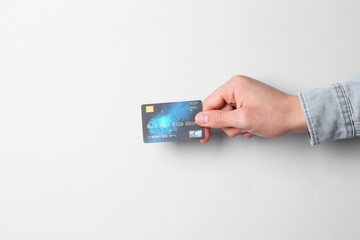 Man holding credit card on light grey background, closeup