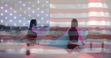 Image of flag of usa over happy diverse women with surfboards on beach in summer