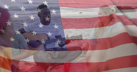 Naklejka premium Image of flag of usa over happy diverse friends playing guitar on beach in summer