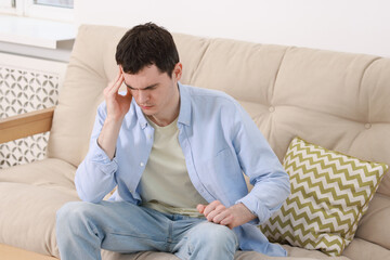 Man suffering from headache on sofa at home